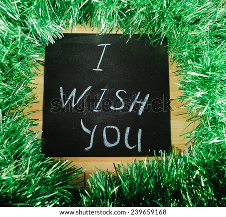  		 on the black Board, white chalk written "I wish you" on the background of green tinsel.