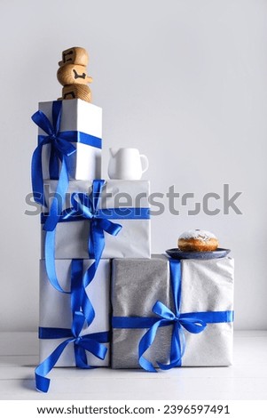 Stack of gifts for Hanukkah celebration, donut, milk and dreidels on table against light background