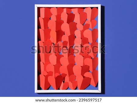 Composition with picture frame and red paper hearts on color background. Valentines Day celebration