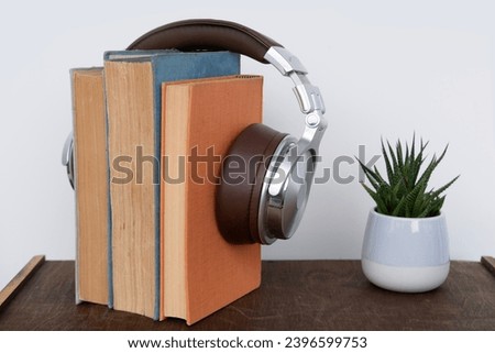 stack of books with headphones, learning foreign languages using audiobooks, multimedia learning, developing reading and listening skills, technology in education