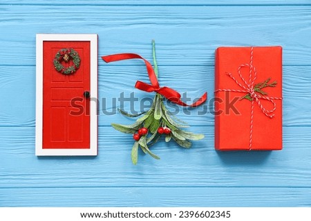 Mistletoe branch with Christmas decorations on blue wooden background