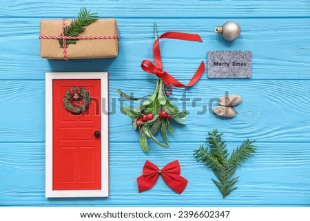 Mistletoe branch with Christmas decorations on blue wooden background