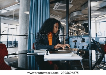 Engrossed Black data analyst in her 30s, meticulously evaluating complex datasets on her laptop  Royalty-Free Stock Photo #2396606875