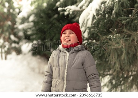 Cute little girl catches snowflakes mouth in winter sunny day. Outdoor winter activity. Happy childhood. Christmas and New Year concept