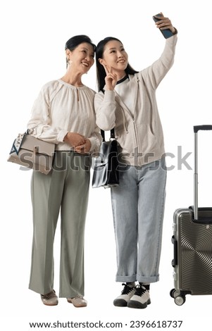 Mother and daughter taking photos on their mobile phones while traveling