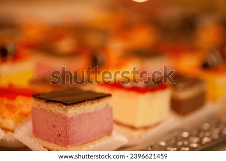 This image offers a glimpse of a dessert tray filled with an assortment of petit fours, captured in a soft focus that creates a dreamy, indulgent atmosphere. The blurred effect draws attention to the