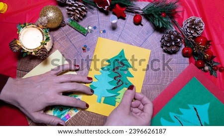 Making Christmas cards, women's hands make cards from folded paper, New Year's and Christmas decorations colorful and glitter
