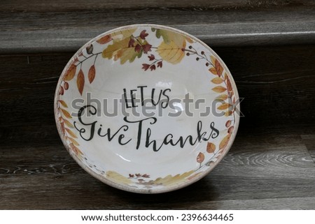 An empty fruit bowl that has the words "Let us give thanks" written inside.