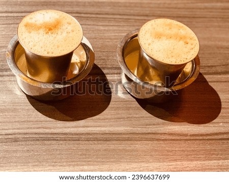The famous south Indian filter coffee traditionally served in a stainless steel tumbler and a dabara.