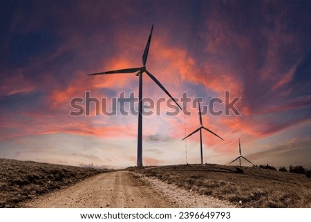 Mountain scenery in winter with snow and a wind farm at sunset. Wind turbines for green economy and technology are the only solution to protect the planet from climate change and global warming  Royalty-Free Stock Photo #2396649793