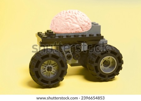 toy car with human brain anatomical model on a yellow background
