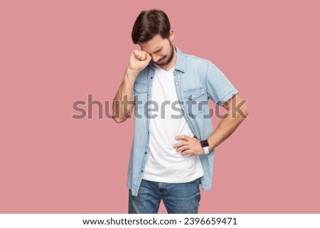 Portrait of depressed crying bearded man standing being in stressful situation stands desperate as faces problem feels regret blames himself in failure. Indoor studio shot isolated on pink background. Royalty-Free Stock Photo #2396659471