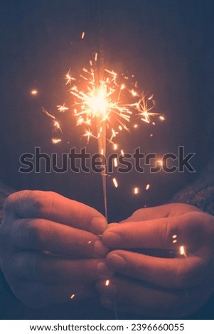 Vertical copy space image of hands holding a fire sparkler to celebrate new year eve or christmas time. People close up for celebration and holiday fun. Freedom and hope. Daydreamer female
