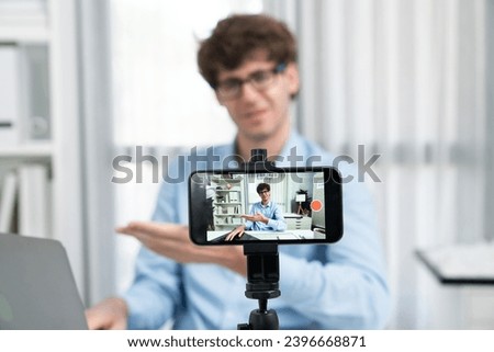 Host channel of influencer using smartphone focusing phone streaming online broadcast in sales and marketing planning with portrait face blurred background on social media at modern office. Gusher.