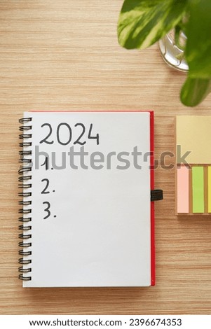 Top view of notebook with 2024 new year's resolutions and goals list and pothos plant over wooden table Royalty-Free Stock Photo #2396674353