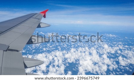 Aerial view from a flying plane in the sky over the clouds. Image of airplane wing flying above the clouds. The clouds are soft and clean like cotton candy.