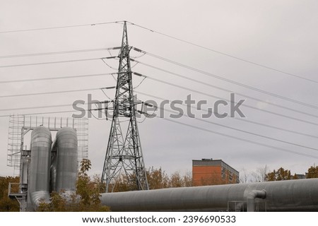 pipeline and power transmission tower close-up against a background of gray sky.
