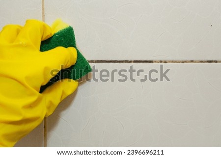 Black mold on bathroom tiles due to dampness.  Clean mold using baking soda and a sponge. Fungus on the seams between tiles. Mold and fungus pores are harmful to human health Royalty-Free Stock Photo #2396696211
