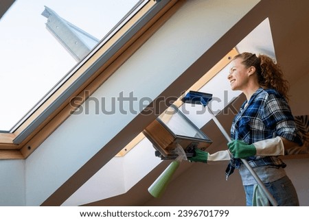 Woman cleans skylight window in her apartment. Housework, cleaning window at home.