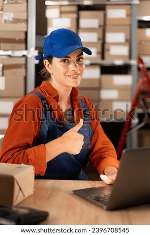 Latin smiling young woman working at small business commerce doing happy thumbs up gesture, looking at the camera showing success. Copy space