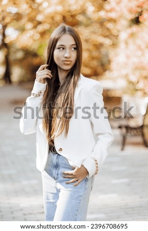 Vertical photo. Beautiful carefree young teenage girl in casual clothes. Portrait of a beautiful girl against the background of nature with a blurred background.