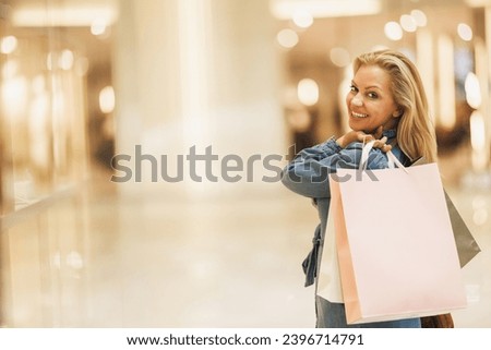 A very happy fashionable woman flaunting her chic shopping haul in a vibrant mall. Looking at camera. Royalty-Free Stock Photo #2396714791