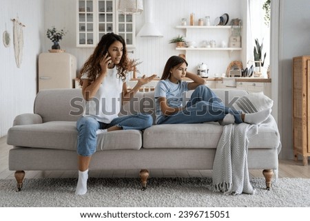 Emotional anxious mother arguing, swearing by phone in front of child at home, unhappy upset teen girl daughter listening her parent mom talking with school teacher about bad grades. Toxic parent Royalty-Free Stock Photo #2396715051