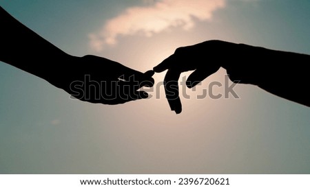 Finger Touching hands, silhouette of man, woman in sun, couple feels love. Reunion of loved ones, family happiness. Gentle touch with fingers of hands in sunset. Black hands touching each other