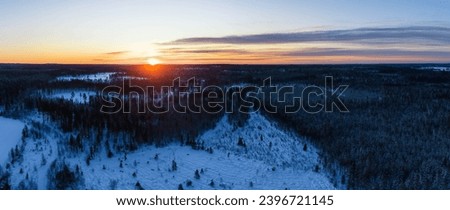 Winter cold red Sunset - the Sun hides behind the horizon line, snowy forest landscape of Northern Scandinavian landscape in Lapland, Sweden. Aerial photo panorama