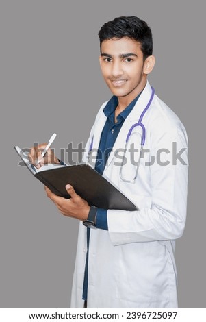 He was writing something while carrying a book with a very smiling face. Dressed in a blue suit with a white coat and bone coat, it shows him writing a happy report about his patient.