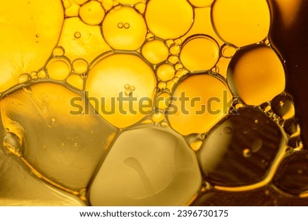 Gold drops of oil or serum texture background. Abstract gold fluid with bubbles. Macro shot Royalty-Free Stock Photo #2396730175