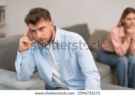 Millennial couple facing family conflict on sofa at home, upset and unhappy man turns away from his wife partner, hinting at issues of infidelity or jealousy in their marriage. Selective focus Royalty-Free Stock Photo #2396733171