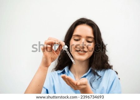 Girl is holding pipette with hyaluronic serum or acid in hands. Young woman with acid dropper in hands Royalty-Free Stock Photo #2396734693