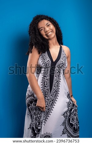 Beautiful young woman with curly hair looking at the camera against blue background.