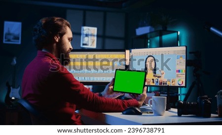 Freelancer following tutorial on green screen tablet, learning how to build digital portfolio showcasing edited images. Photo editor watching guide on mockup device about using retouching software