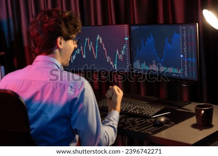 Successful business trader raising fist up with highest profit looking on global market online in real time at neon light modern office. Concept of dynamic stock exchange young businessman. Gusher.