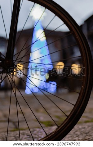 In Hondarribia's winter square, an abstract bike wheel shines with festive bokeh elegance.