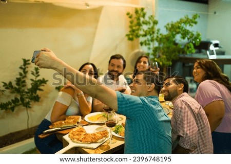 Dinner host taking a selfie with his group of friends coming to eat and drink alcohol at his home backyard