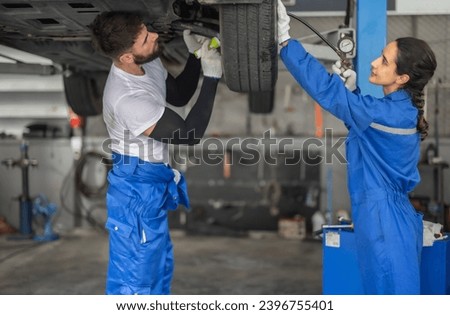 Car service technicians examine, analyze, diagnose wheel and tire issues in garage workshop. Using precise tools to detect, troubleshoot, repair problems, ensuring optimal balancing and alignment. Royalty-Free Stock Photo #2396755401
