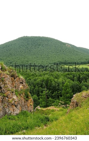 A look through a stone crevice in the mountains to the slope of a high mountain overgrown with dense coniferous forest. Khakassia, Siberia, Russia. Royalty-Free Stock Photo #2396760343