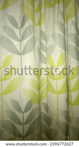 In the following picture is a photo of a mosquito net with a black and green leaf pattern 