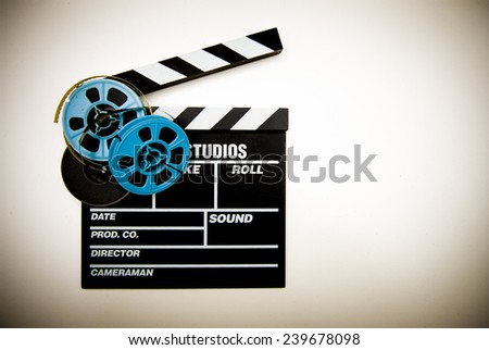Clapper board with 8mm film reels in white background and vintage color effect