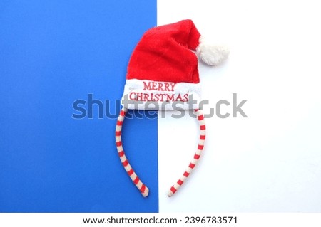 Beautiful headband 
 Decorative red Santa Hat   isolate on a blue and white backdrop.
concept of joyful Christmas party,New year is coming soon, festive season decoration with Christmas elements