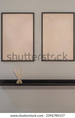 Vertical photo of the minimalist home decoration with two blank frames on a wall