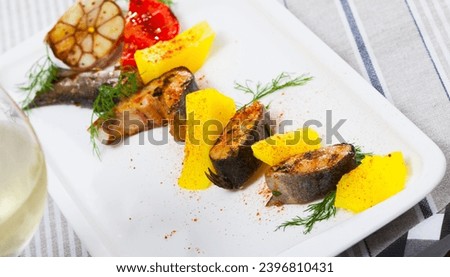 Picture of tasty baked rainbow trout steaks with potatoes and greens on white plate