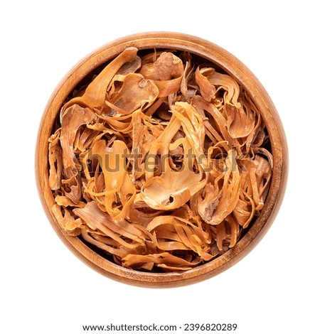 Dried mace in a wooden bowl. Spice with pale yellow and orange tan, made of seed coverings of nutmeg seeds, with similar flavor, but more delicate. Used to flavor food and in preserving and pickeling. Royalty-Free Stock Photo #2396820289
