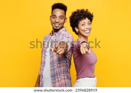Young leader couple two friend family man woman of African American ethnicity wearing purple casual clothes together point index finger camera on you isolated on plain yellow orange background studio.