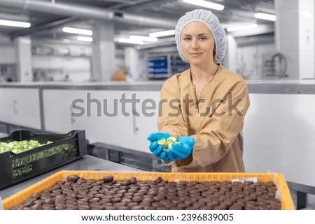 Chocolate factory woman worker work on production line with sweets candy. Concept control food industry.