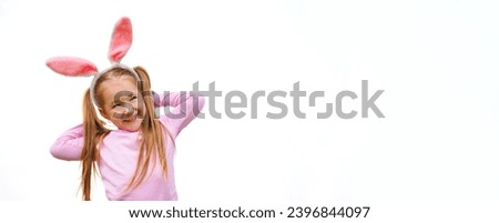 Cute happy caucasian girl two or three years old wearing rabbit ears smiling, standing by white wall. Concept of spring and Easter holiday celebrating.Copy space.Half body shot. Place for text
