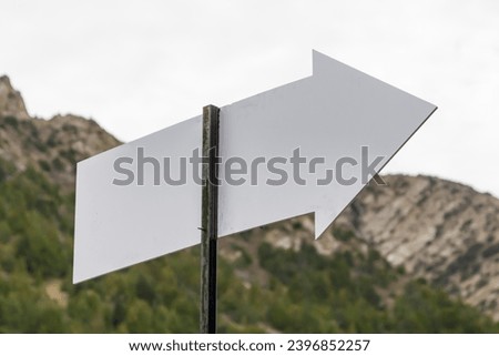 Signposts in the mountains. Blank white arrow-shaped sign in the mountains